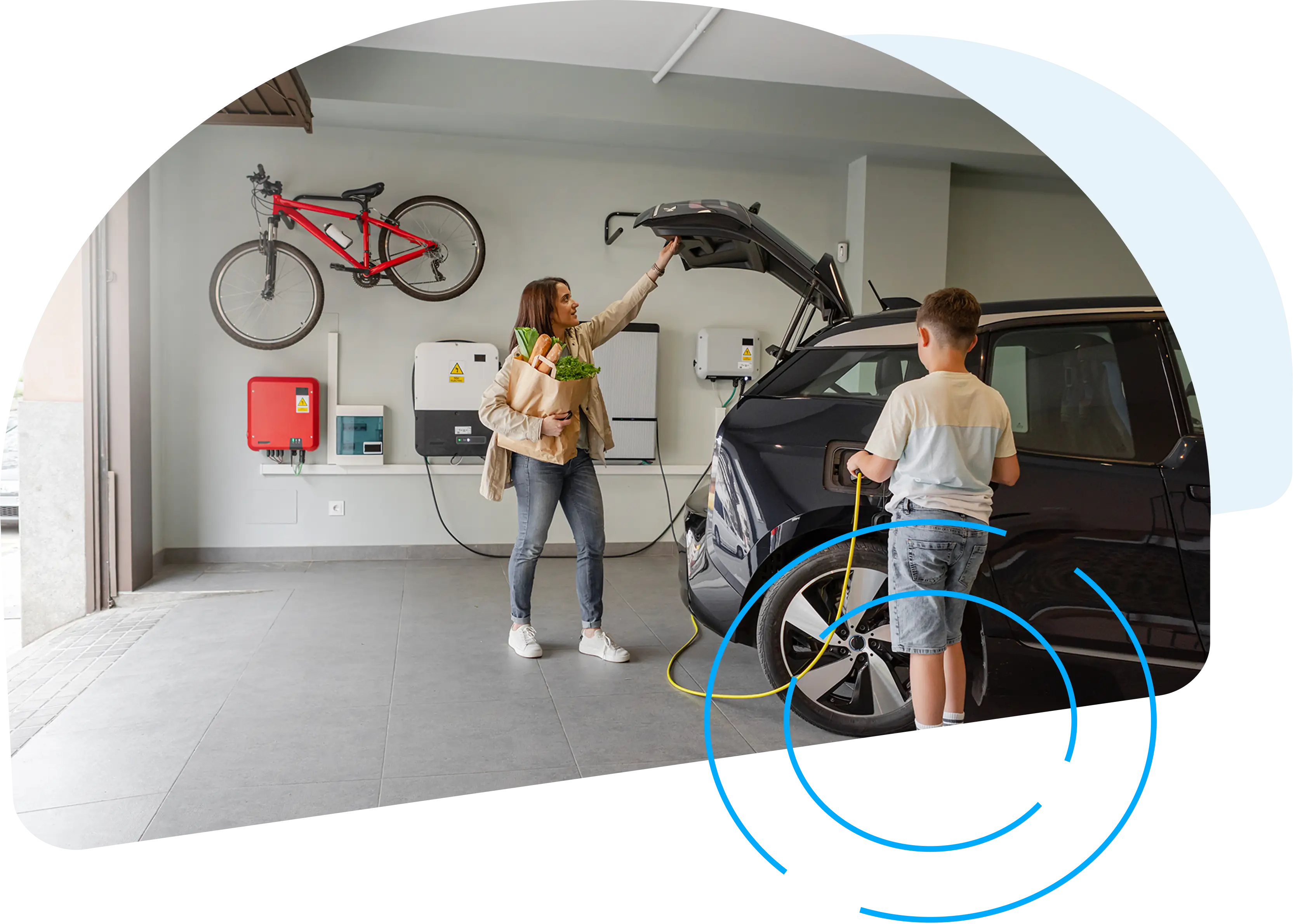 A mother unloads groceries from her EV while her son plugs the EV charger into the car socket.
