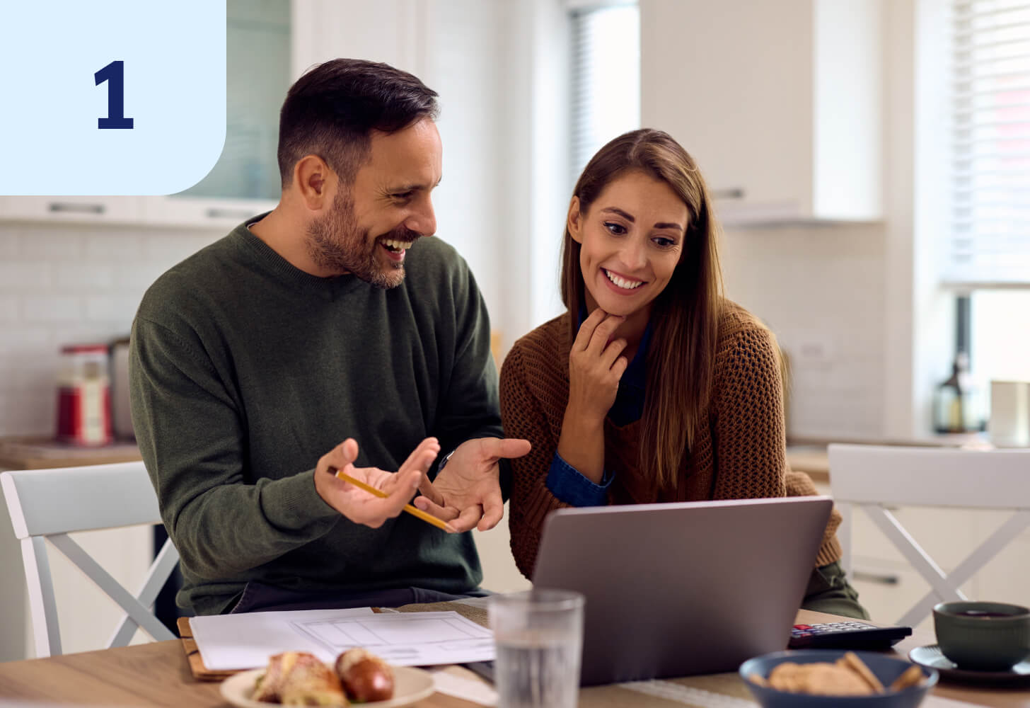 Two people chatting while looking at a laptop