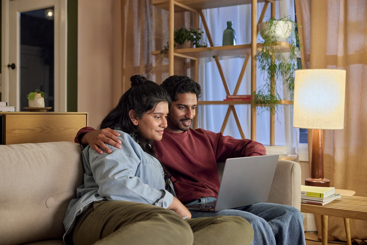 A couple using a laptop together at home.