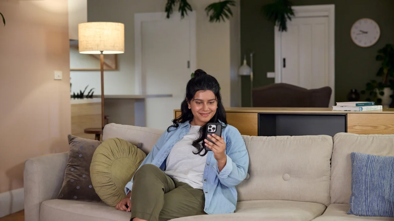 A woman using her phone while sitting on the couch in the living room