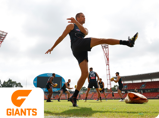 A GWS Giants football player kicking the ball during practice
