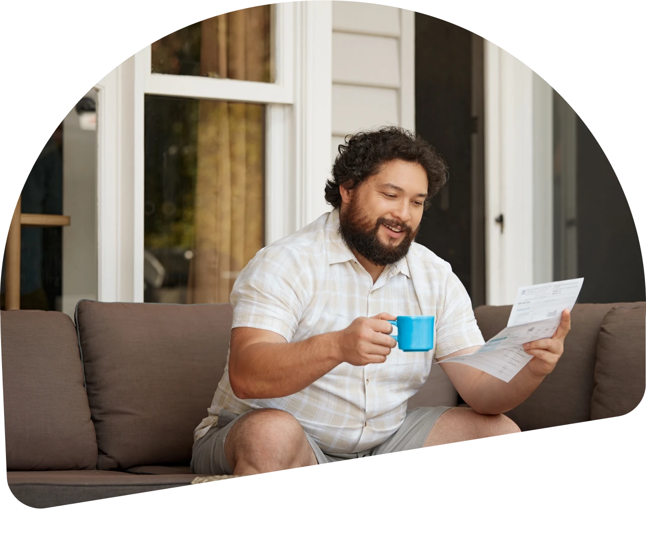 A man sitting on the outdoor deck of his home, reading his bill.