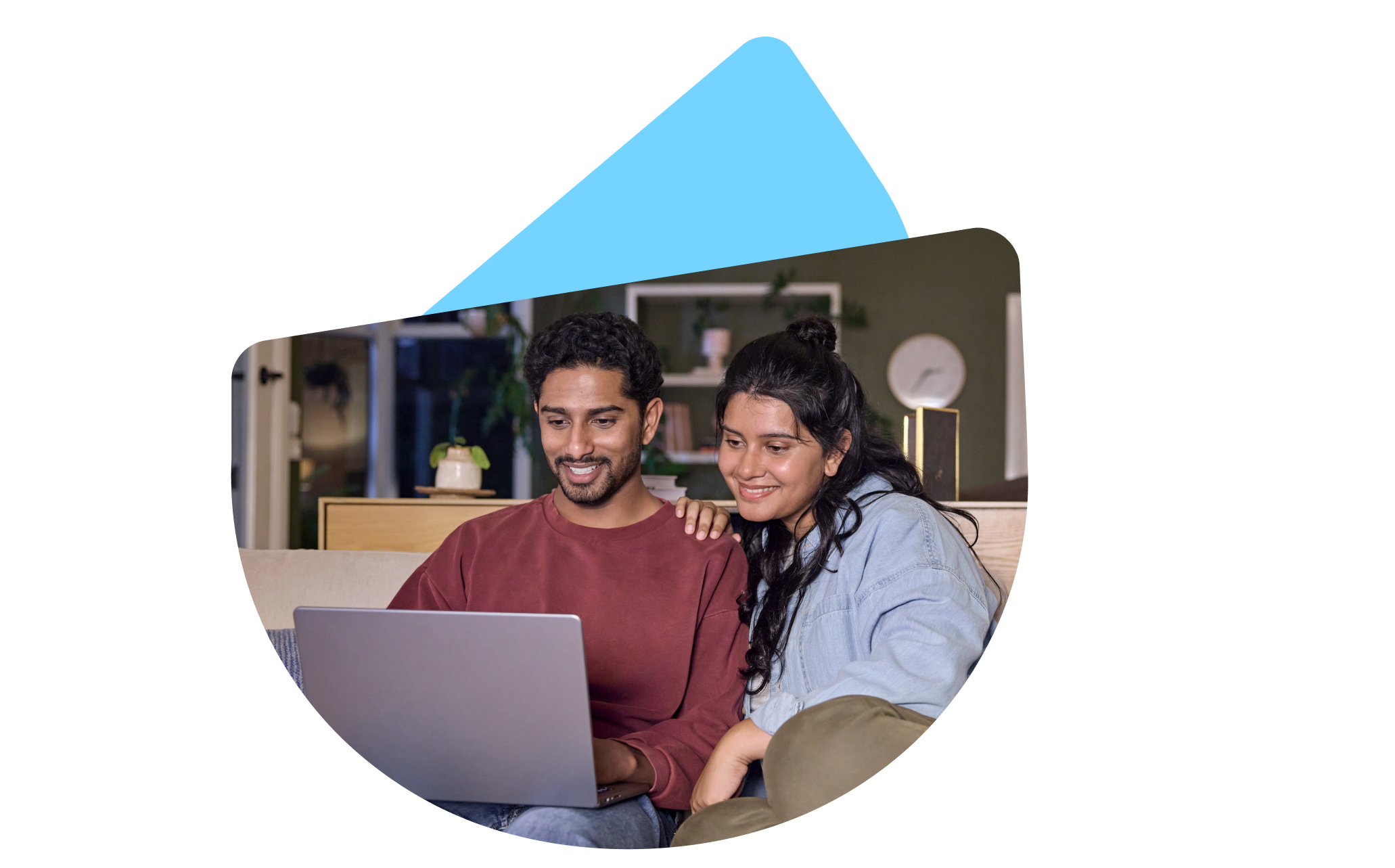 A couple using a laptop together at home on the living room couch.