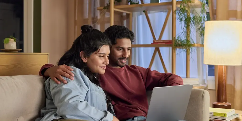 A couple using a laptop together at home.