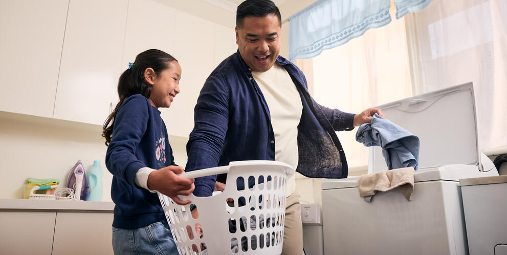 Father and daughter doing laundry together at home
