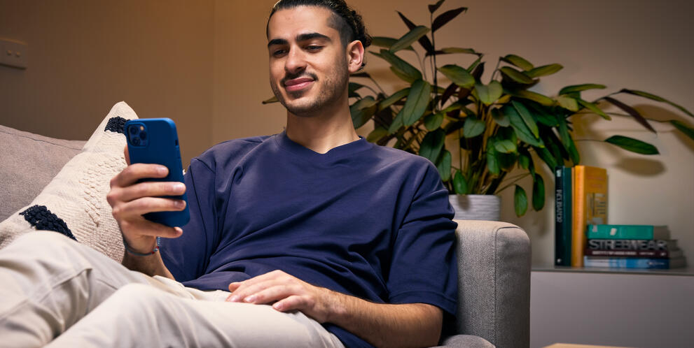Person holding smartphone while relaxing on couch