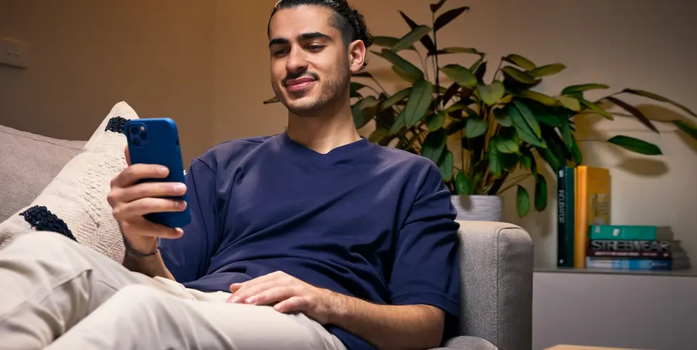 A man using his smartphone while sitting on the living room couch