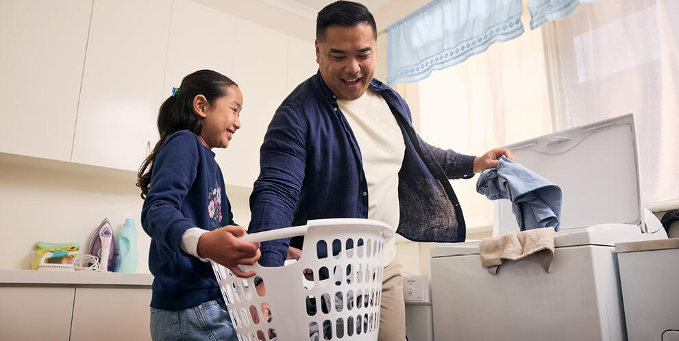 A father and daughter removing dry clothes from the washing machine.