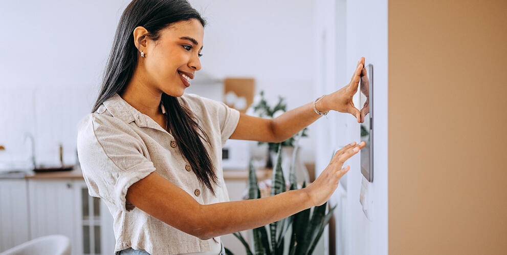 A woman using a thermostat at home.