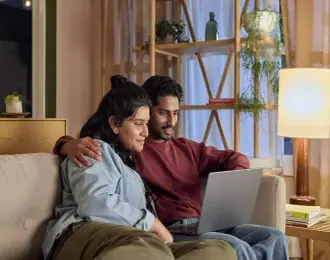 A couple using a laptop together at home.