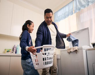 Father and daughter doing laundry together at home