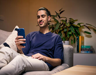 Person holding smartphone while relaxing on couch
