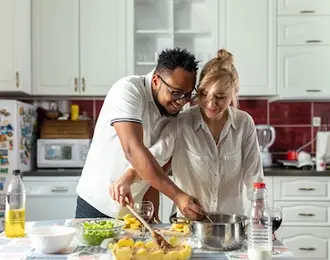 A couple cooking together in the kitchen.