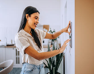 A woman using a thermostat at home.