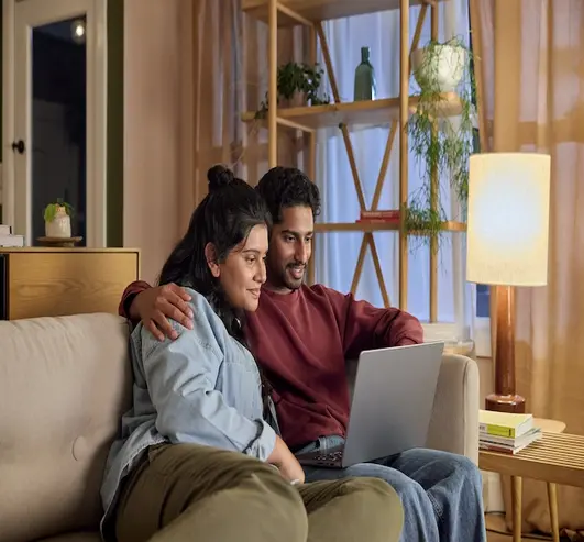 A couple using a laptop together at home.