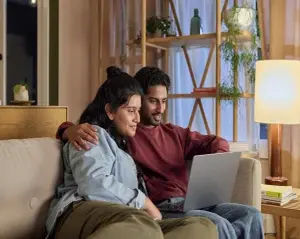 A couple using a laptop together at home.